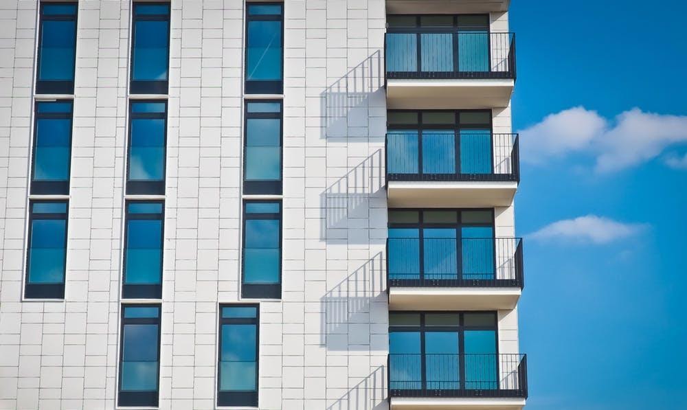 white apartment complex blue skies demand